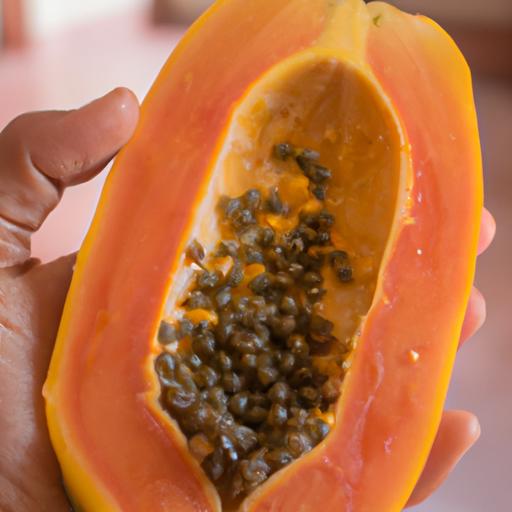 A hand holding a fully ripe papaya fruit with a sweet aroma and soft flesh.