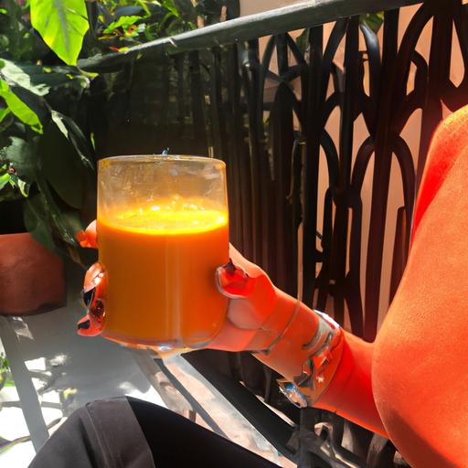 A person holding a glass of papaya smoothie with a calcium supplement bottle next to it.